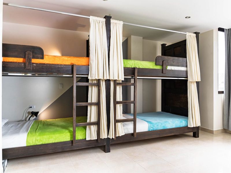 Dormitorio compartido: dos literas de madera con cortinas de privacidad.