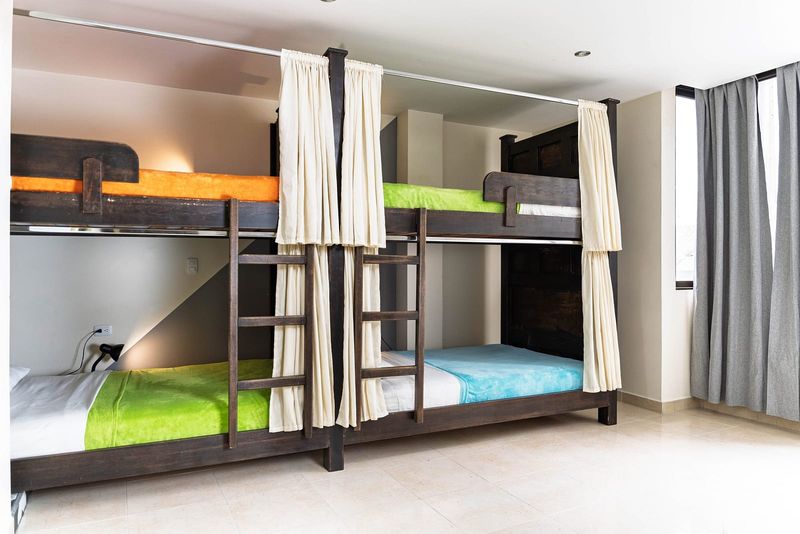 Dormitorio compartido: dos literas de madera con cortinas de privacidad.