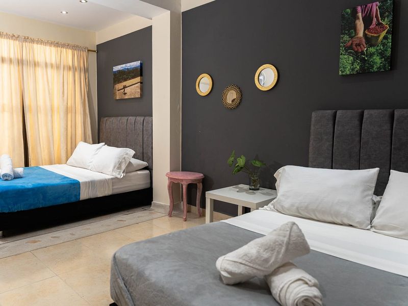 Habitación Geisha: dos camas dobles, pared oscura con espejos dorados y cortinas claras.