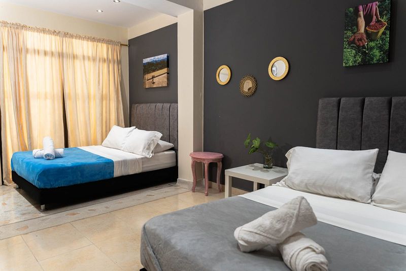Habitación Geisha: dos camas dobles, pared oscura con espejos dorados y cortinas claras.